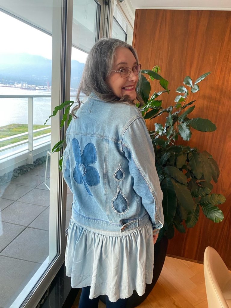 Up-cycled denim jacket modeled, showing flower patchwork and raindrops.